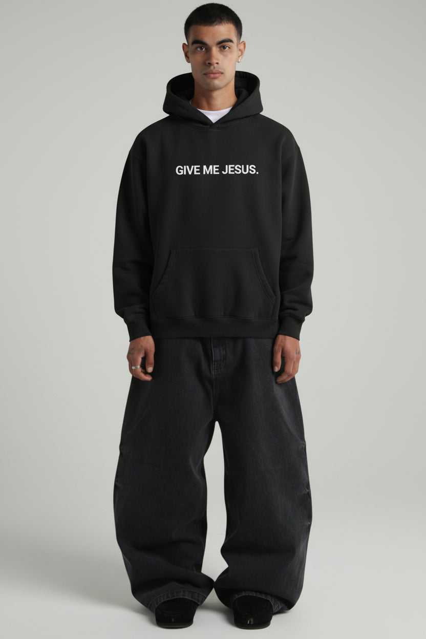 Person wearing a black hoodie with 'Give Me Jesus' text on a plain background