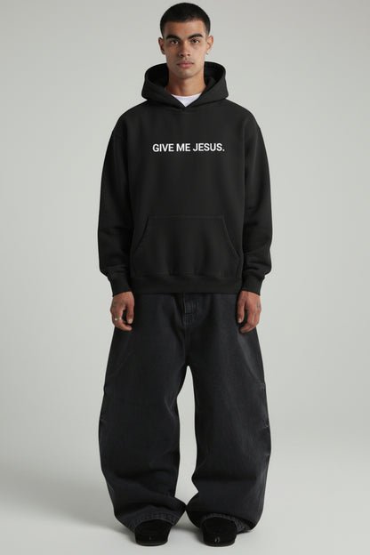 Person wearing a black hoodie with 'Give Me Jesus' text on a plain background